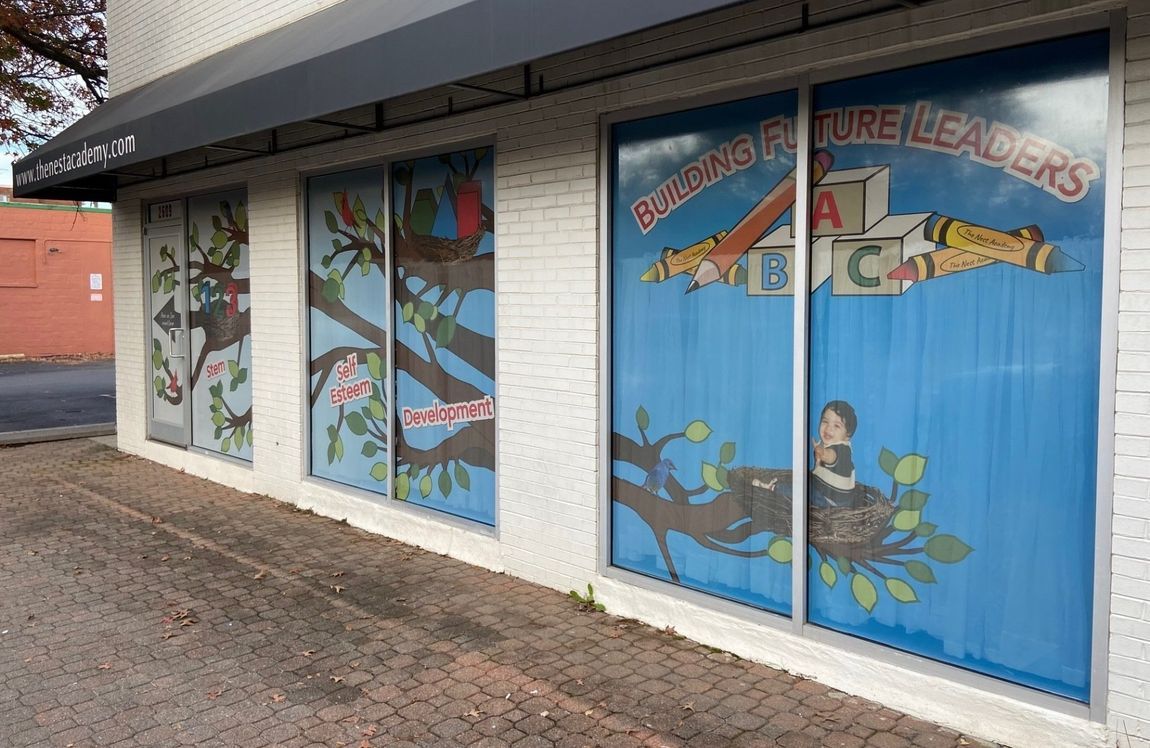 Storefront windows with colorful cartoon murals and blue blinds under an awning