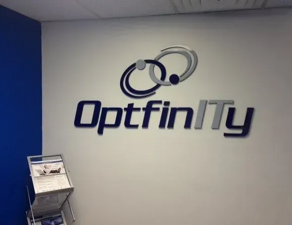 The OptfinITy company logo, featuring stylized circular elements, displayed in blue and gray on a white office wall.