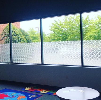 Indoor play area with large frosted windows, colorful floor mat, and a small round white table