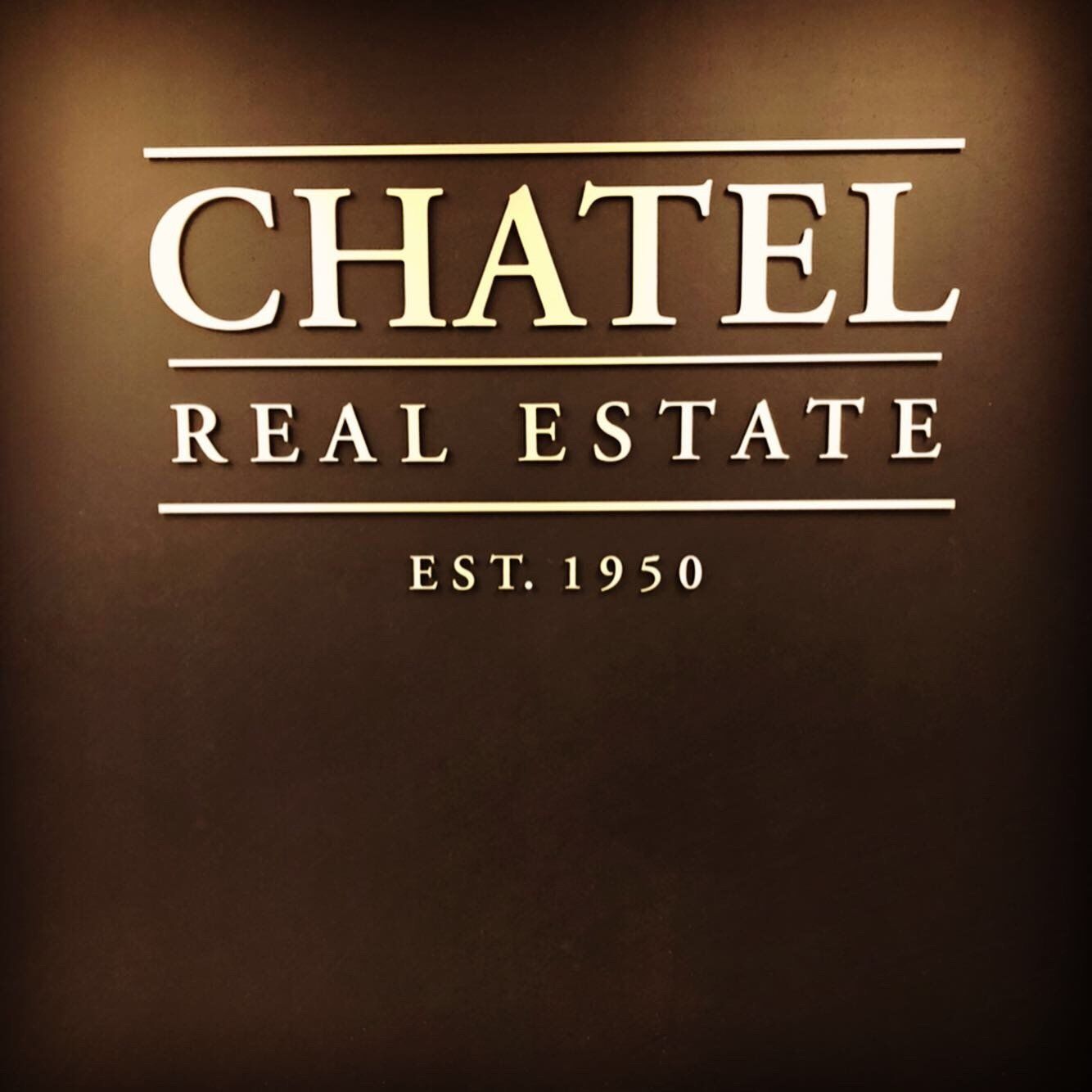 Chatel Real Estate logo in white serif text on a brown background, est. 1950