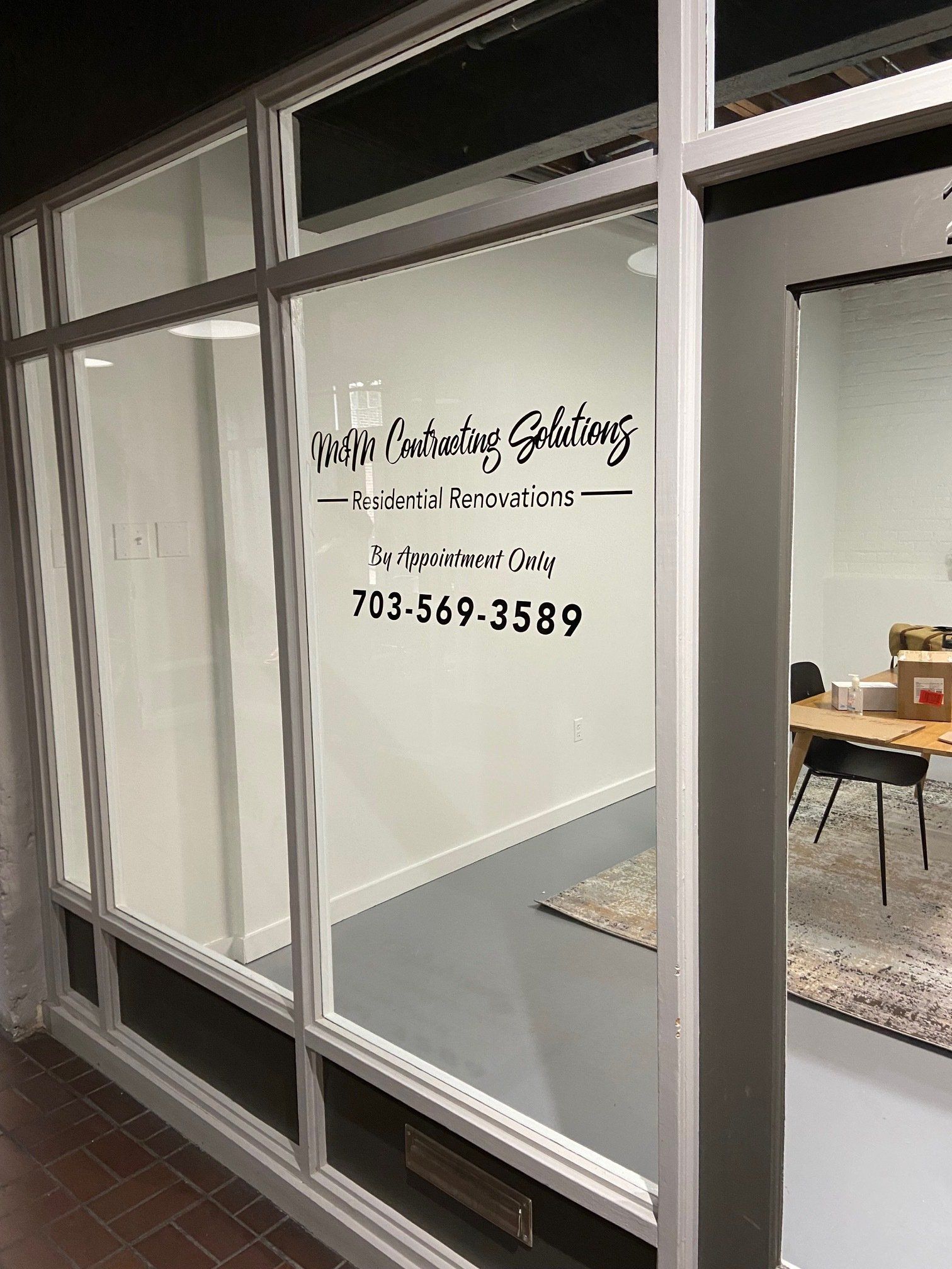 Glass storefront with white interior wall signage and phone number inside an office space