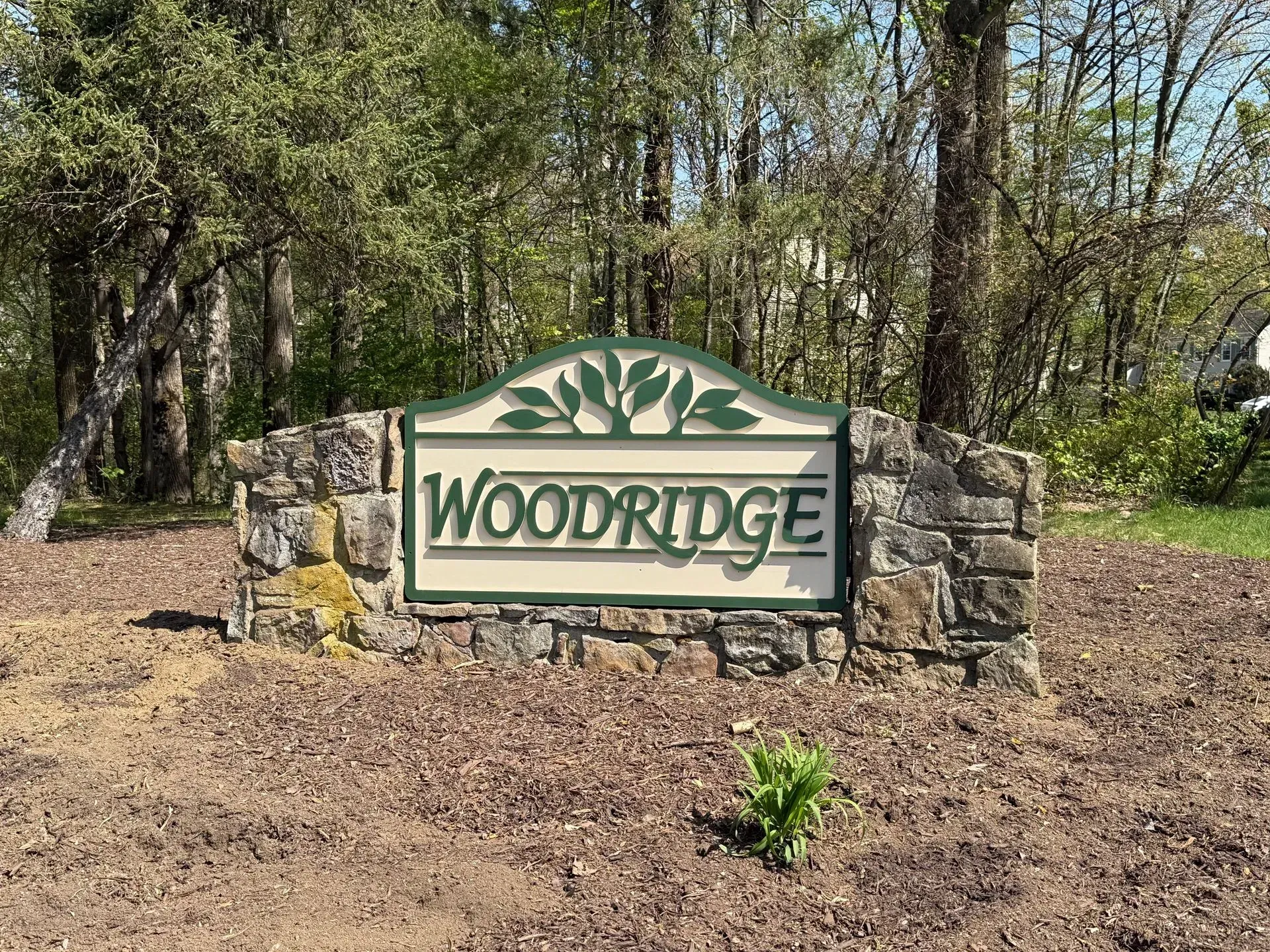 Woodridge neighborhood sign in front of trees and stone landscaping