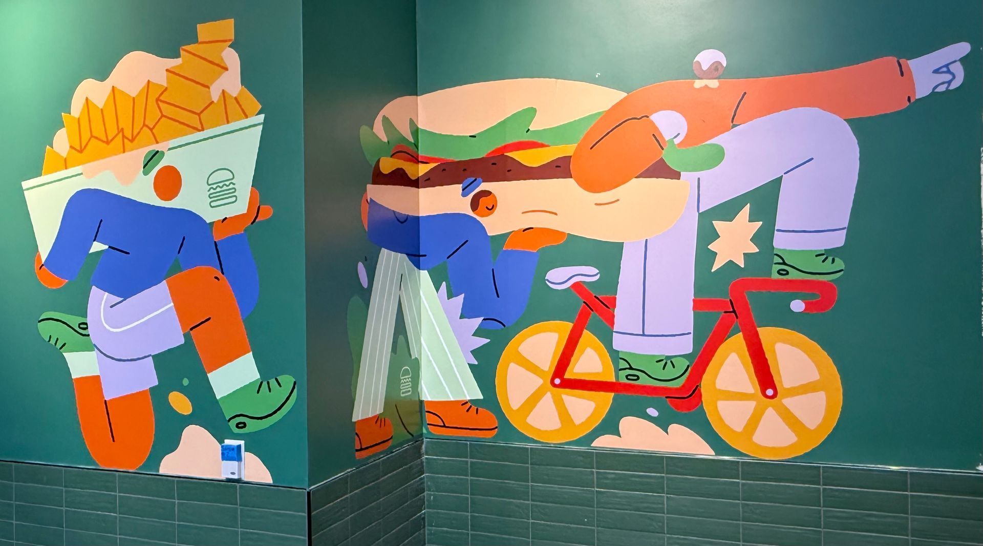 Colorful mural of a cyclist riding a pink bike with a red parrot and abstract green and orange shapes