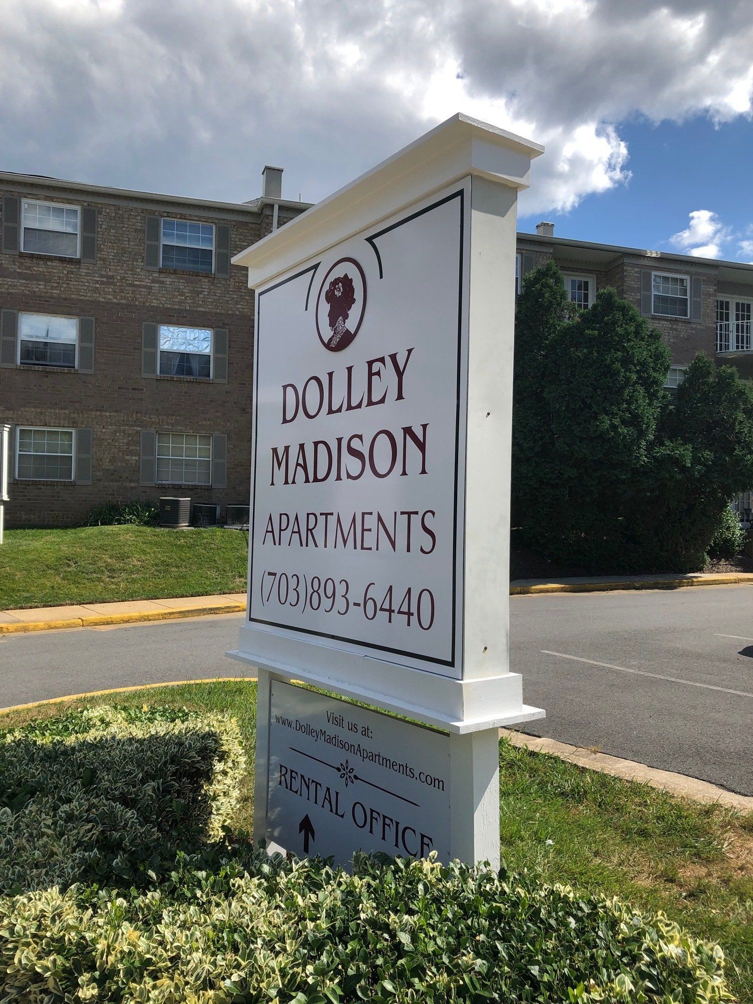 Dolley Madison Apartments sign in a landscaped courtyard with brick buildings behind it