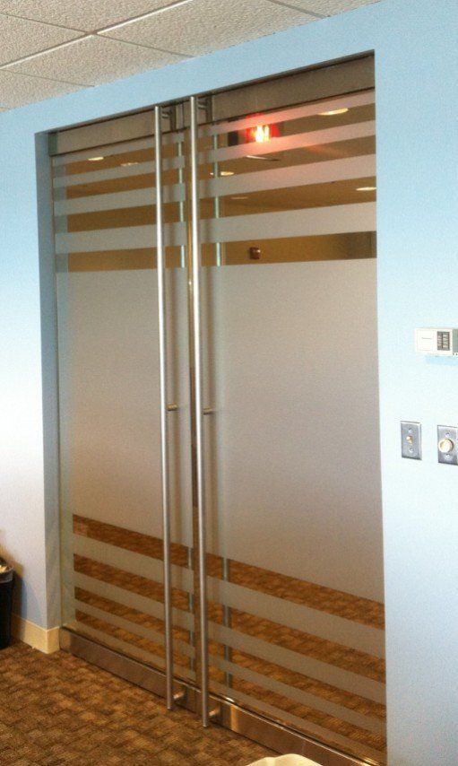 Glass double doors with frosted panels and metal handles in a hallway