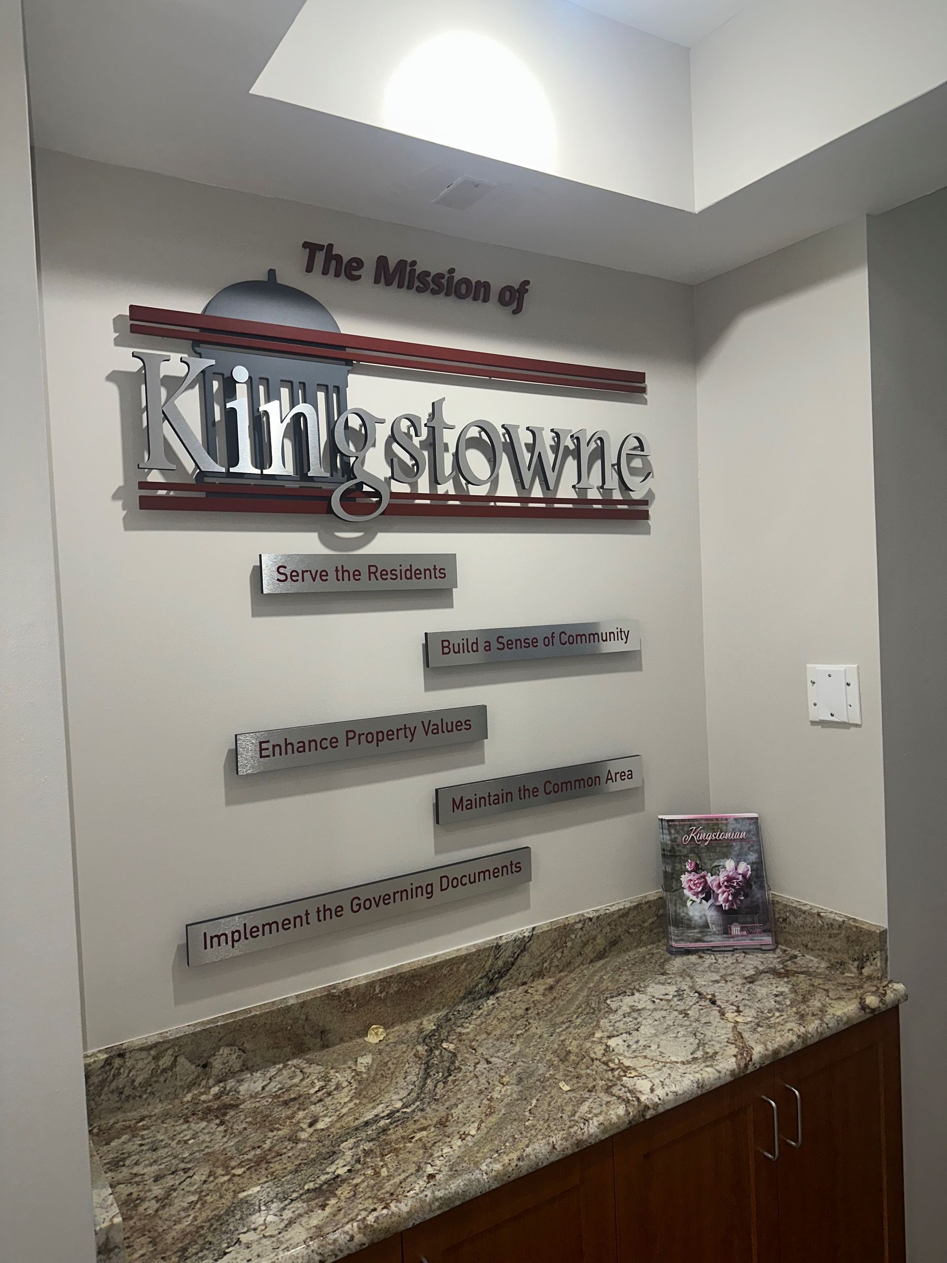 Wall sign in a lobby reading “The Massage of Kim’s Spa” above a granite counter