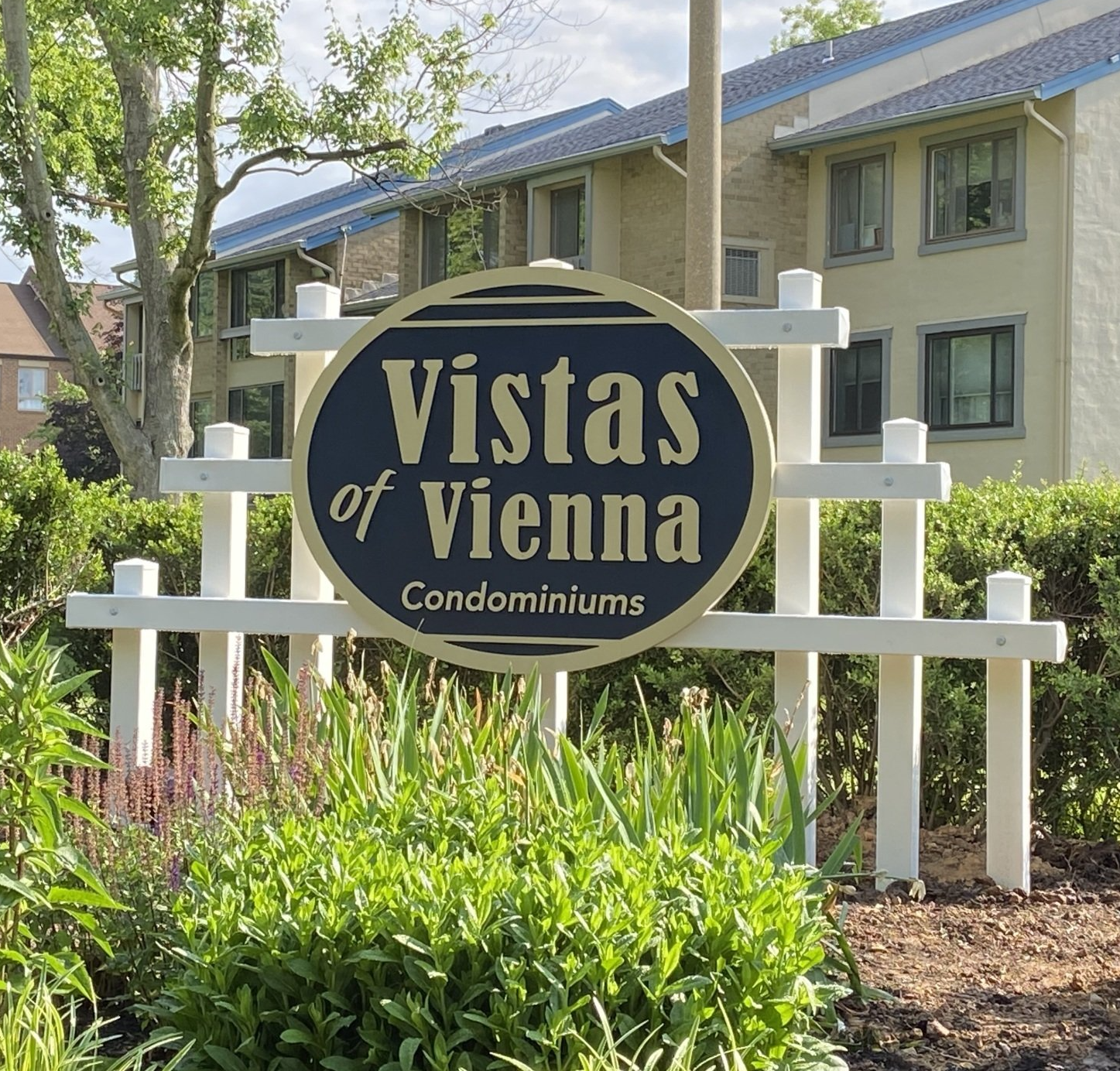 Vistas of Vienna Condominiums sign in front of beige apartment buildings and green landscaping
