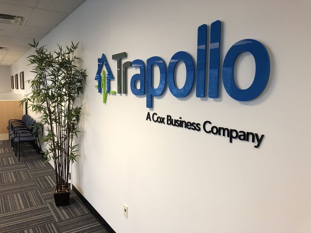 Trapoilo office hallway with blue logo sign on a white wall and potted plants along the corridor