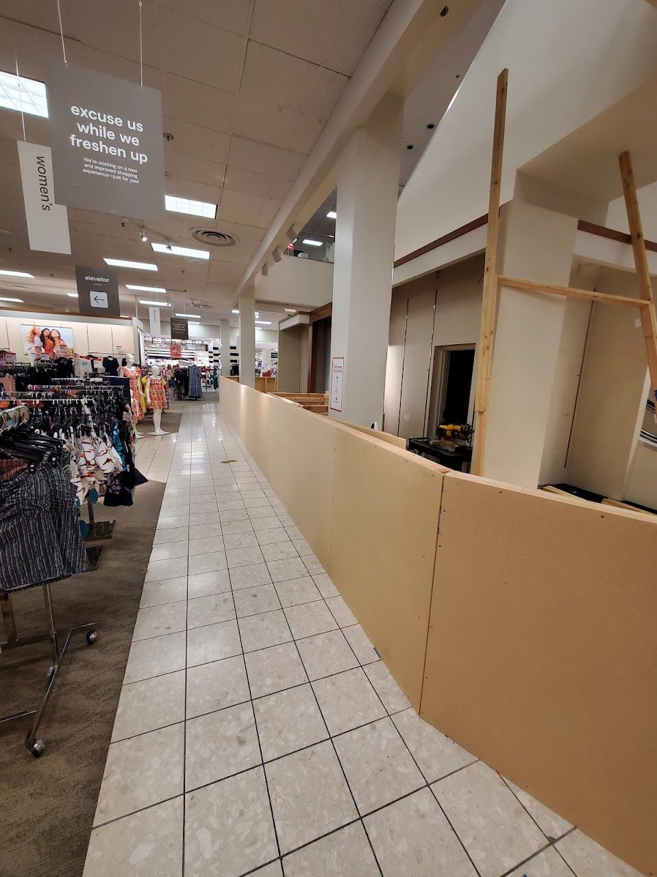 A long hallway in a store with a sign that says ' ladies ' on it