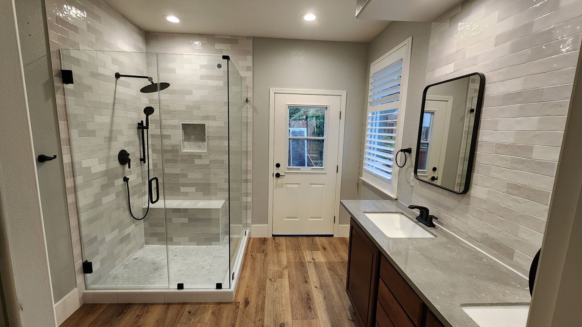 A bathroom with a walk in shower , sink and mirror.