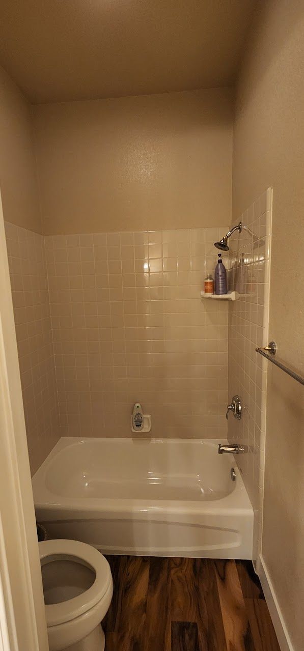 A bathroom with a toilet , bathtub and shower.