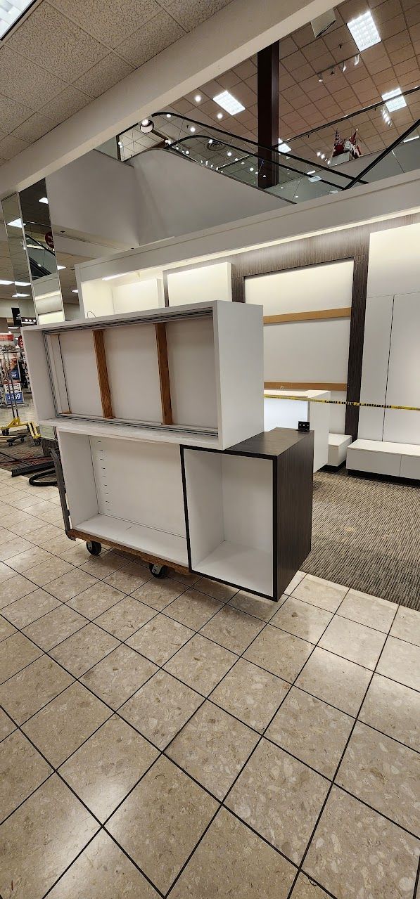 A store with a lot of empty shelves and a escalator in the background.