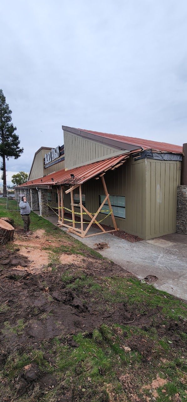 A building with a red tile roof is being built in a field.