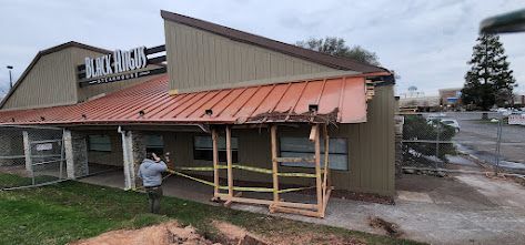 A man is standing in front of a building that is being remodeled.