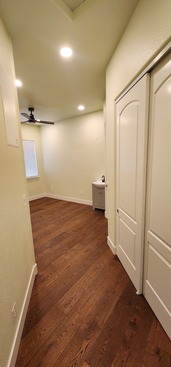 A hallway with hardwood floors and white doors in a house.
