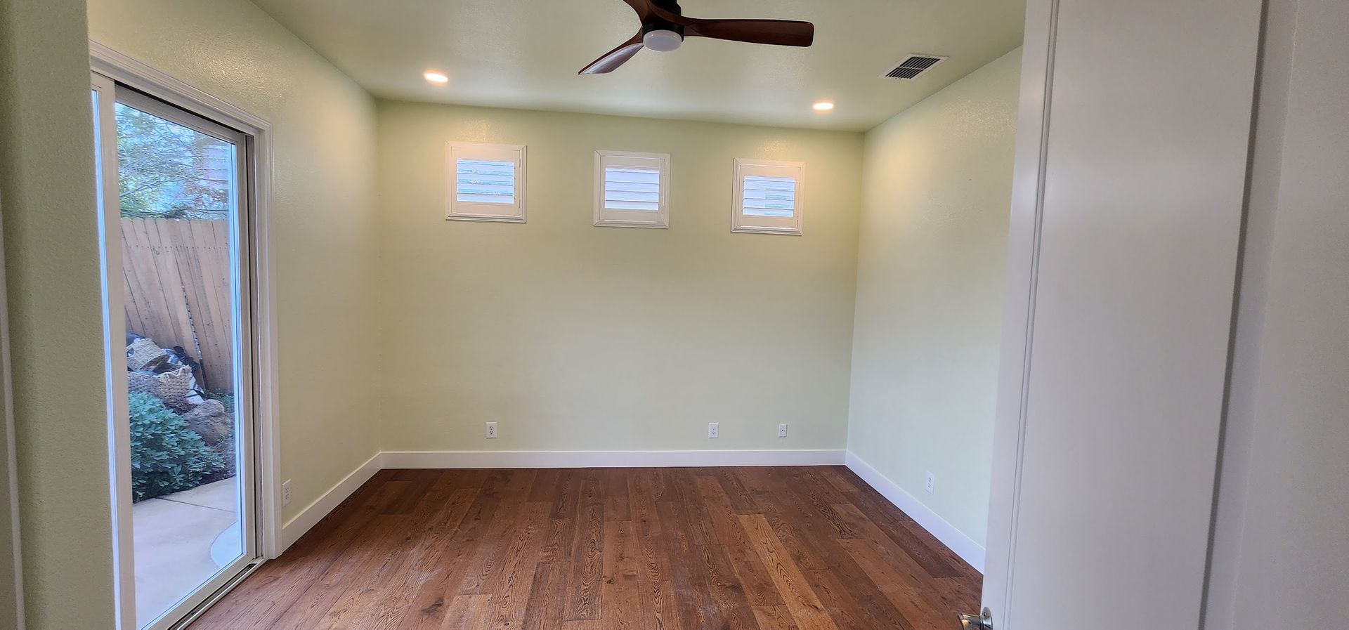 An empty room with hardwood floors and a ceiling fan.