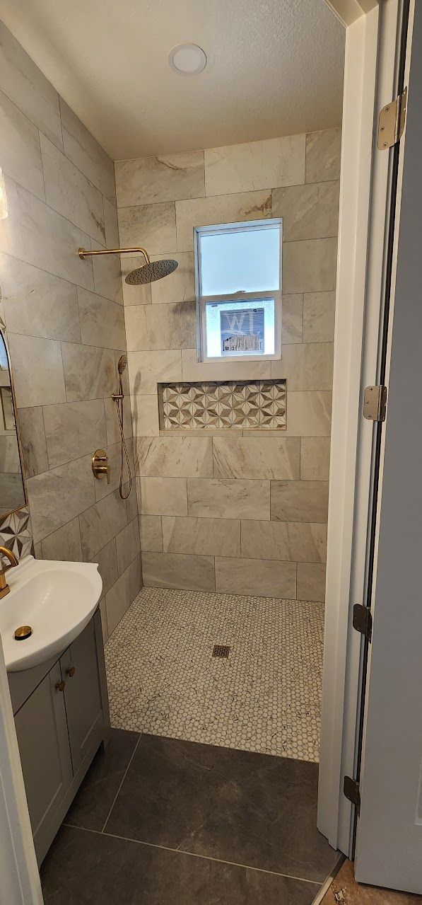 A bathroom with a walk in shower , sink , and window.