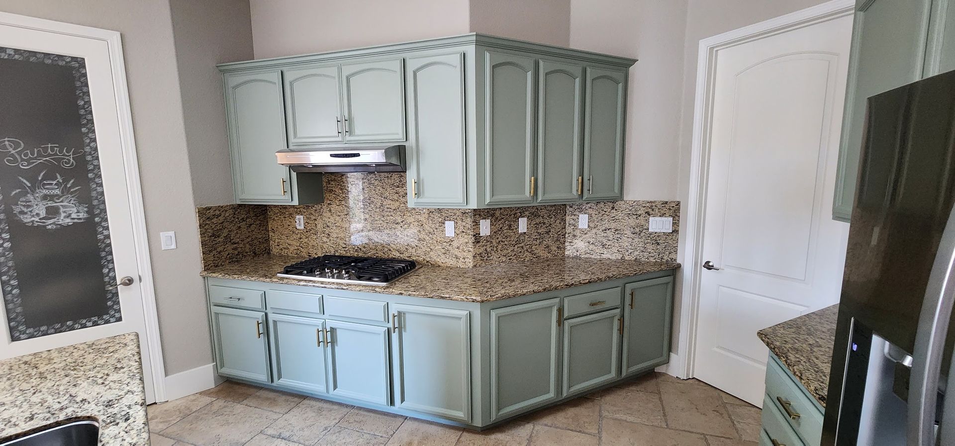 A kitchen with blue cabinets , granite counter tops , a stove and a refrigerator.