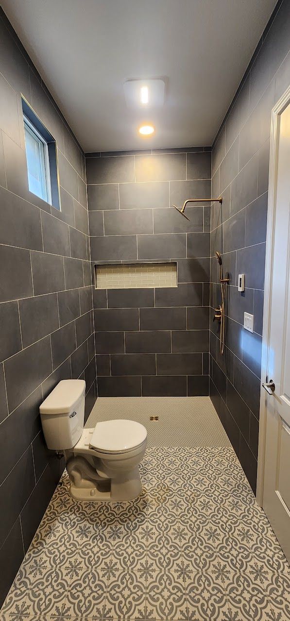 A bathroom with a toilet , shower and window.