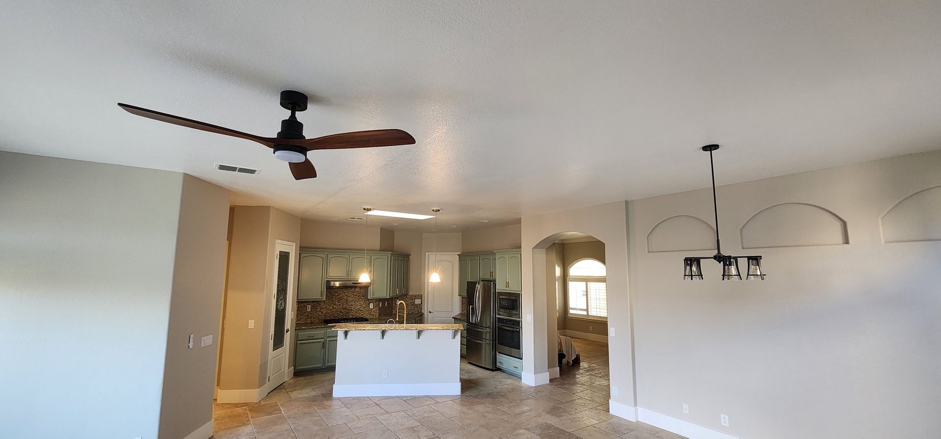 A living room with a ceiling fan and a chandelier.