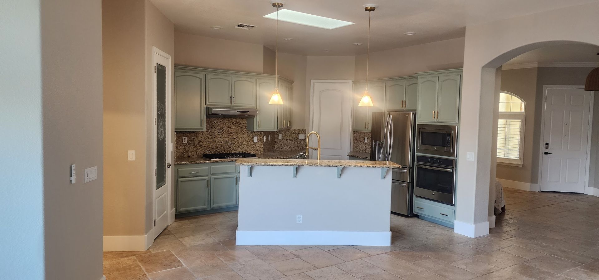 A kitchen with stainless steel appliances and a large island in the middle of the room.