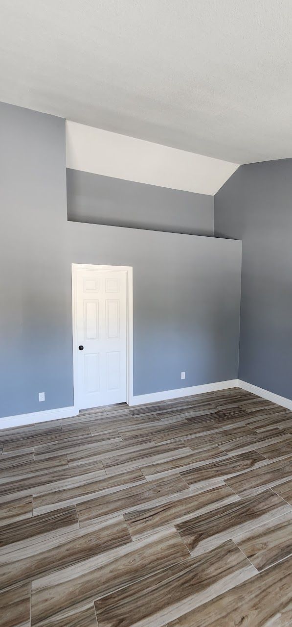 An empty living room with a wooden floor and gray walls.