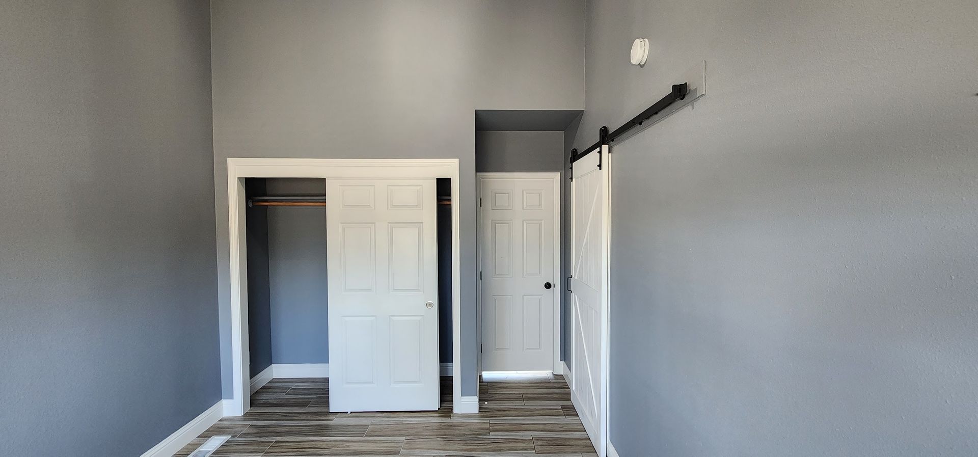 An empty bedroom with a closet and sliding barn doors.