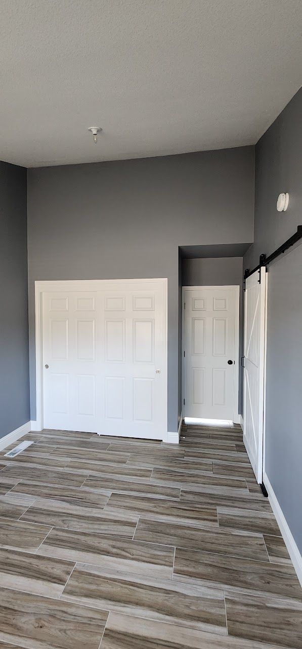 A large empty room with a wooden floor and gray walls.
