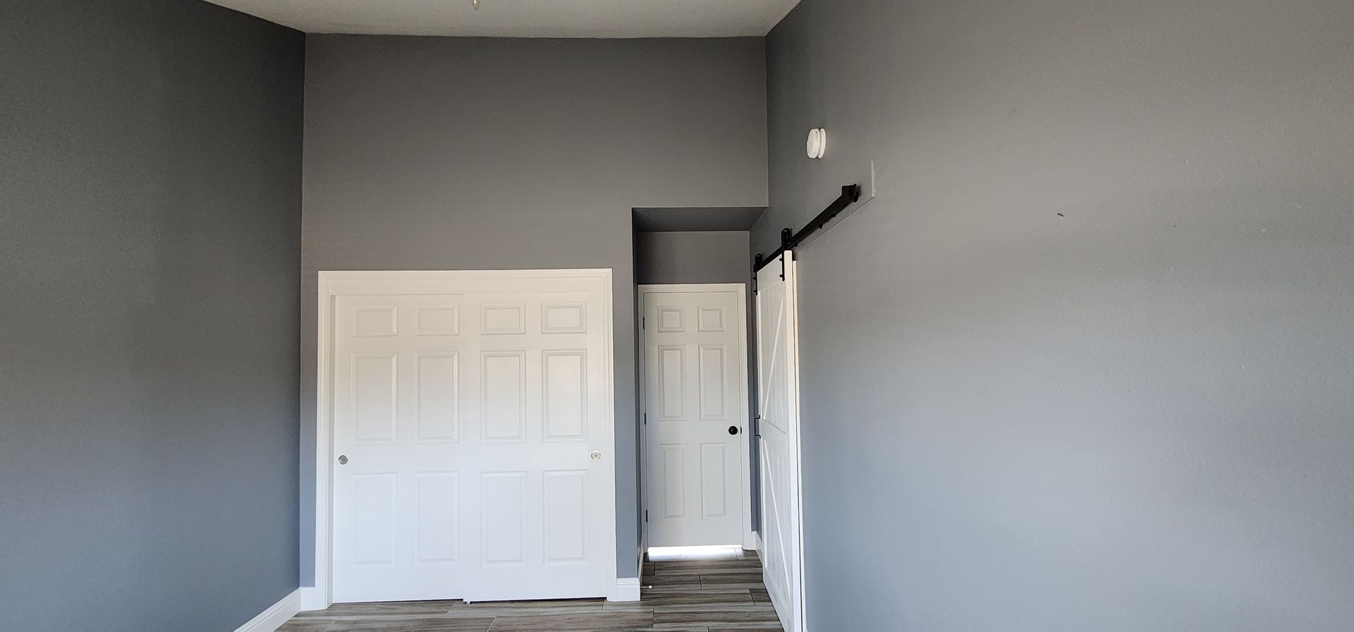 An empty room with gray walls and white doors.