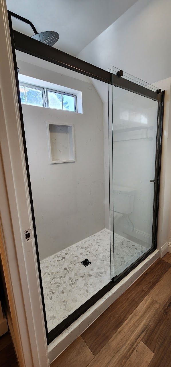 A bathroom with a sliding glass shower door and a window.