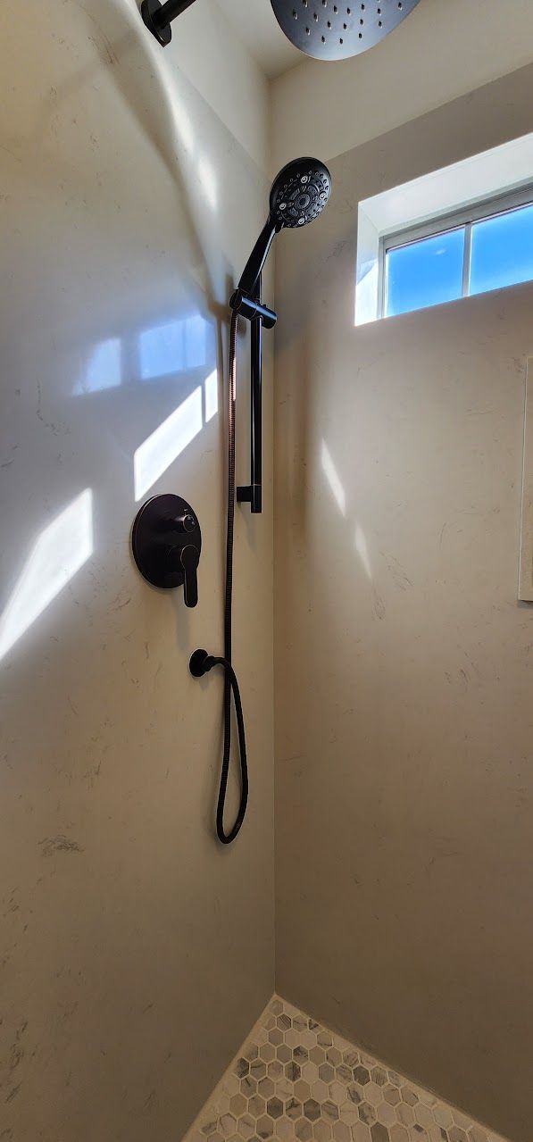A shower with a black shower head and a window.