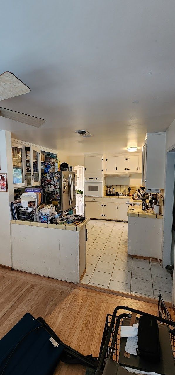 A kitchen with white cabinets , a refrigerator , a sink , and a stove.