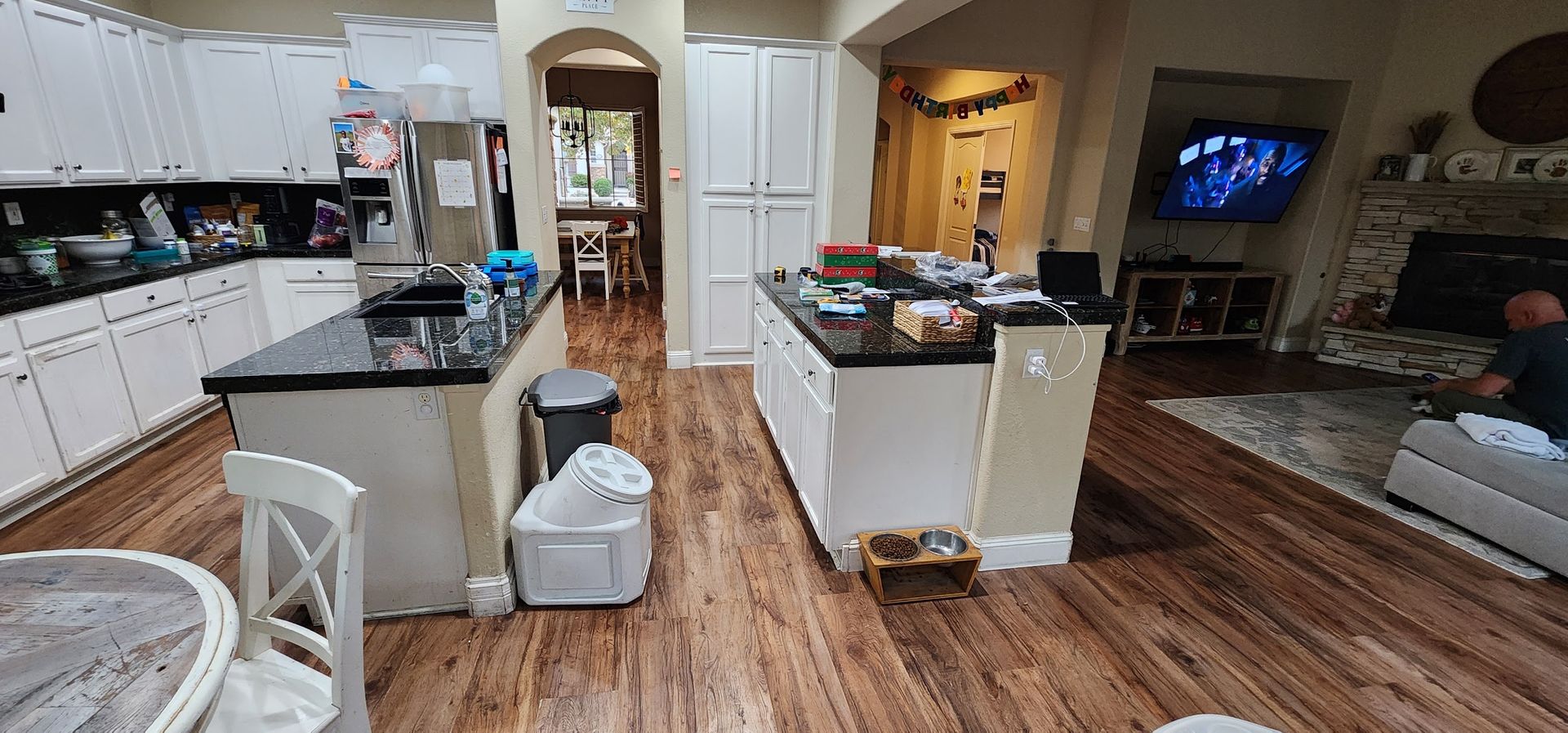 A kitchen with a large island , a table , chairs , and a television.