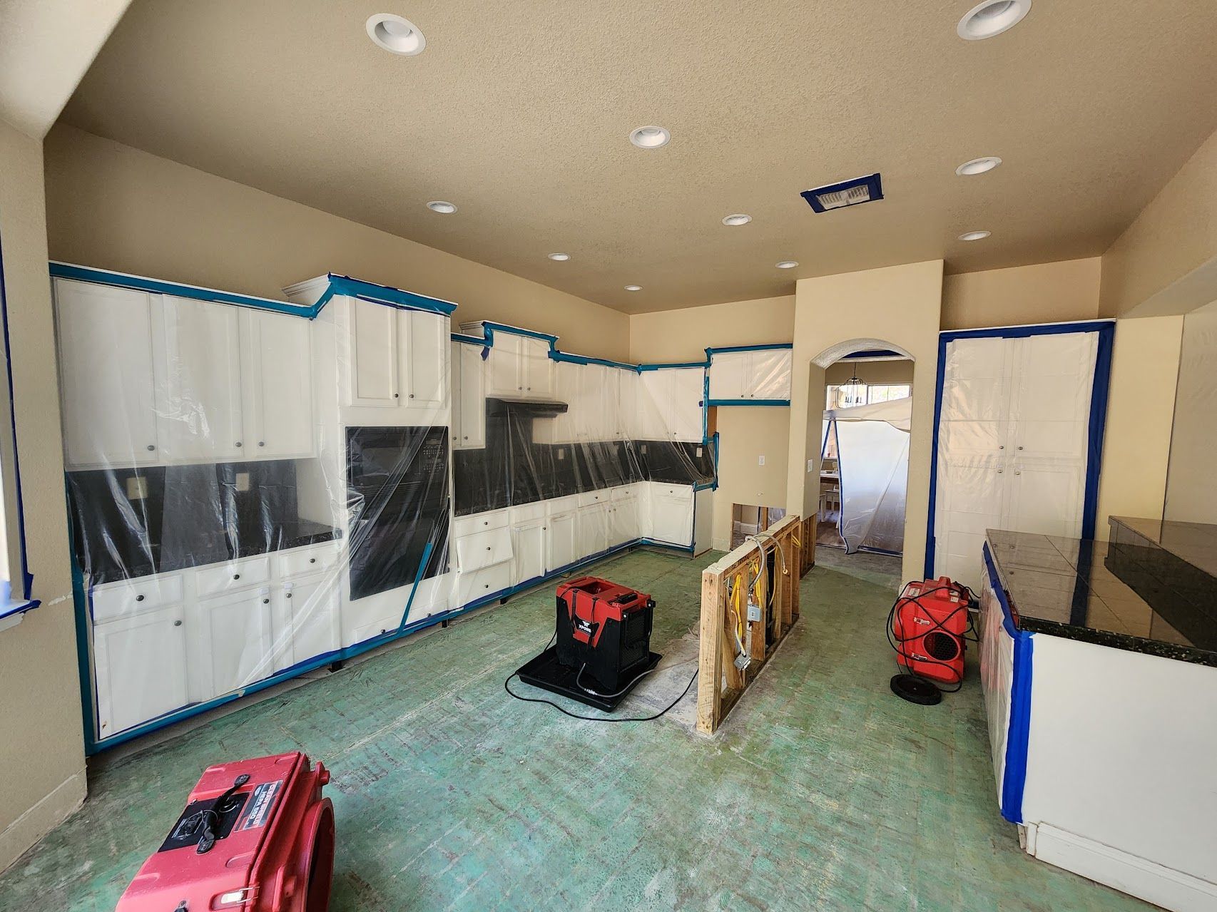 A kitchen with white cabinets and black counter tops is being painted.
