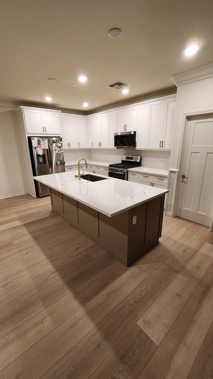 A kitchen with white cabinets and a large island in the middle.