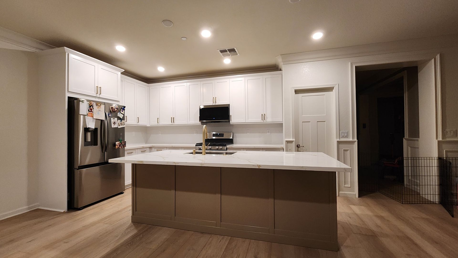 A kitchen with white cabinets , stainless steel appliances , and a large island.