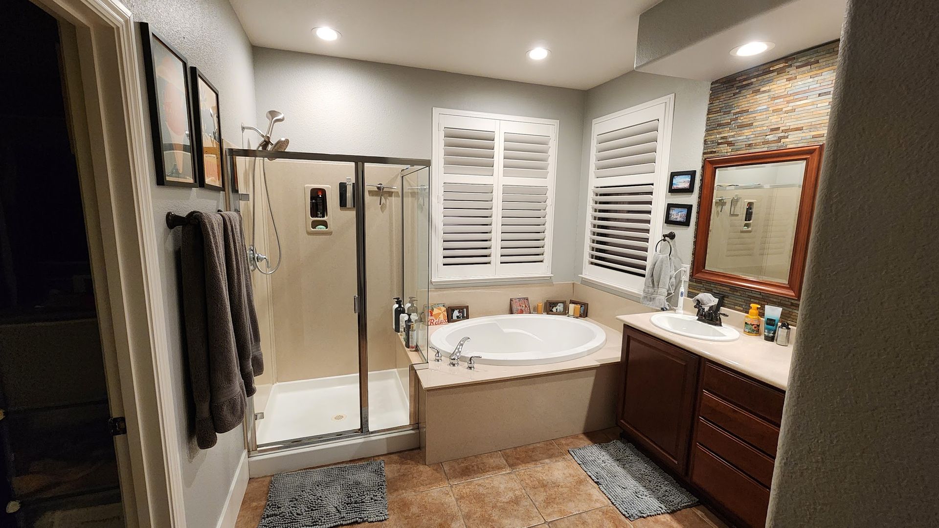 A bathroom with a tub , sink , shower and mirror.