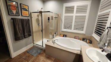 A bathroom with a tub , shower , sink and window.