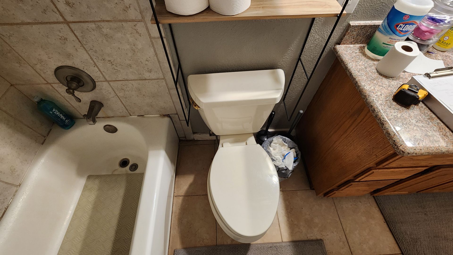 A bathroom with a toilet , sink , bathtub and toilet paper.