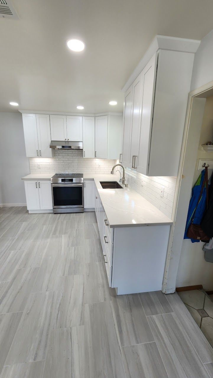 A kitchen with white cabinets , stainless steel appliances , a sink , and a stove.