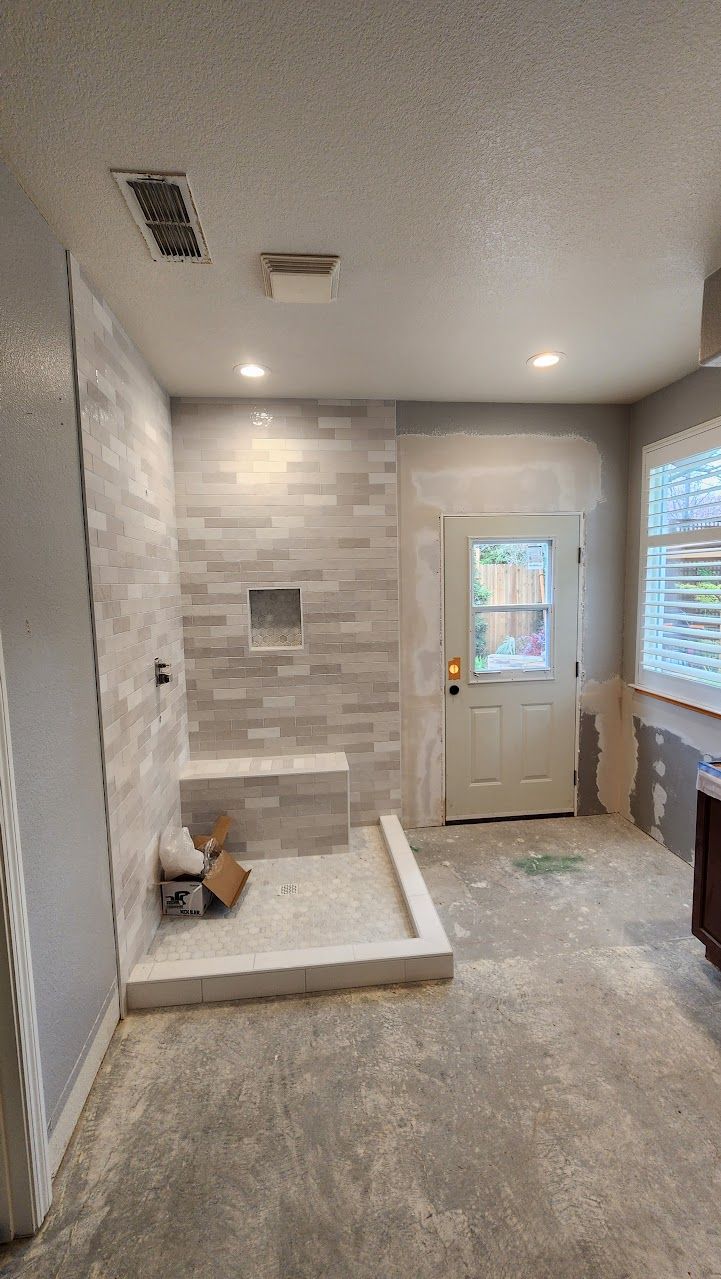 A bathroom under construction with a walk in shower and a window.