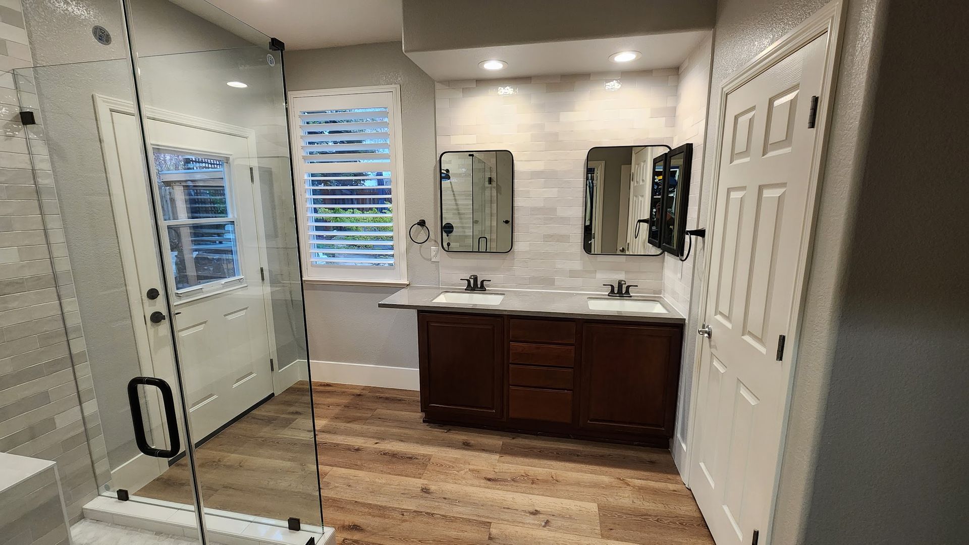 A bathroom with two sinks and a walk in shower.