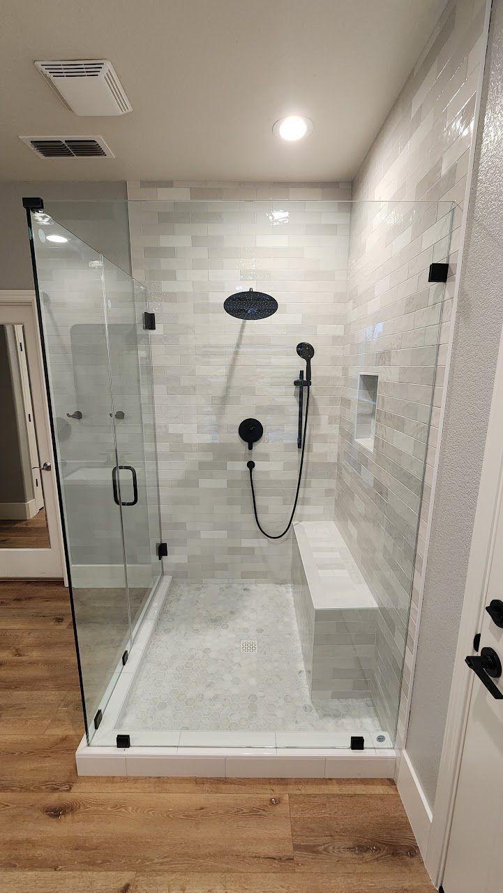 A bathroom with a walk in shower with a bench.