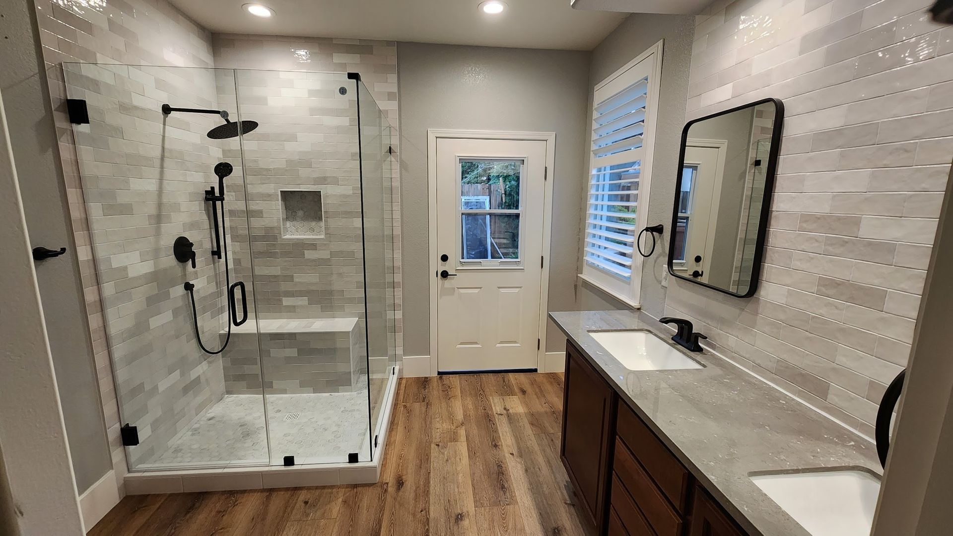 A bathroom with a walk in shower , sink and mirror.