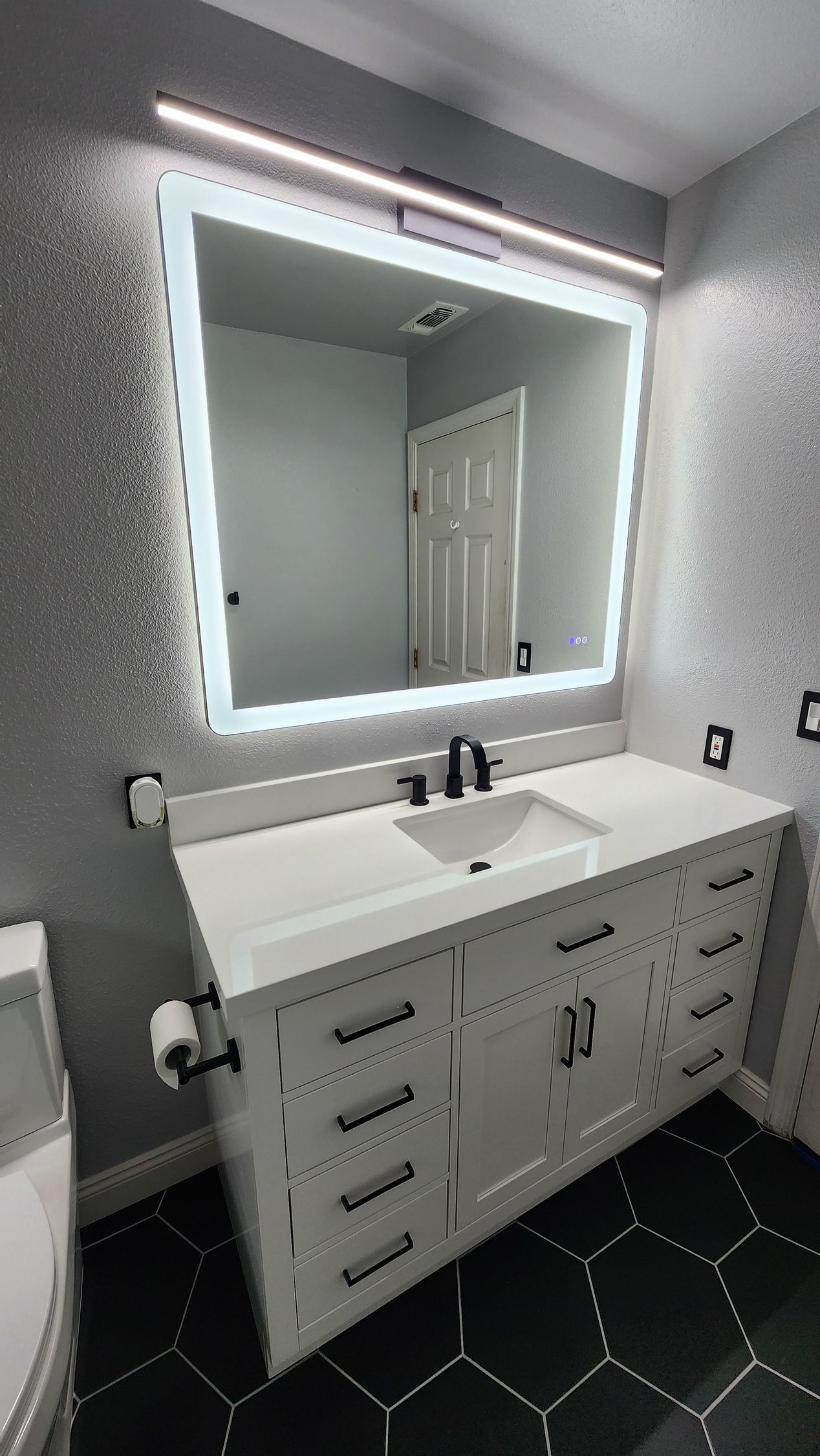 A bathroom with a sink , mirror and toilet.