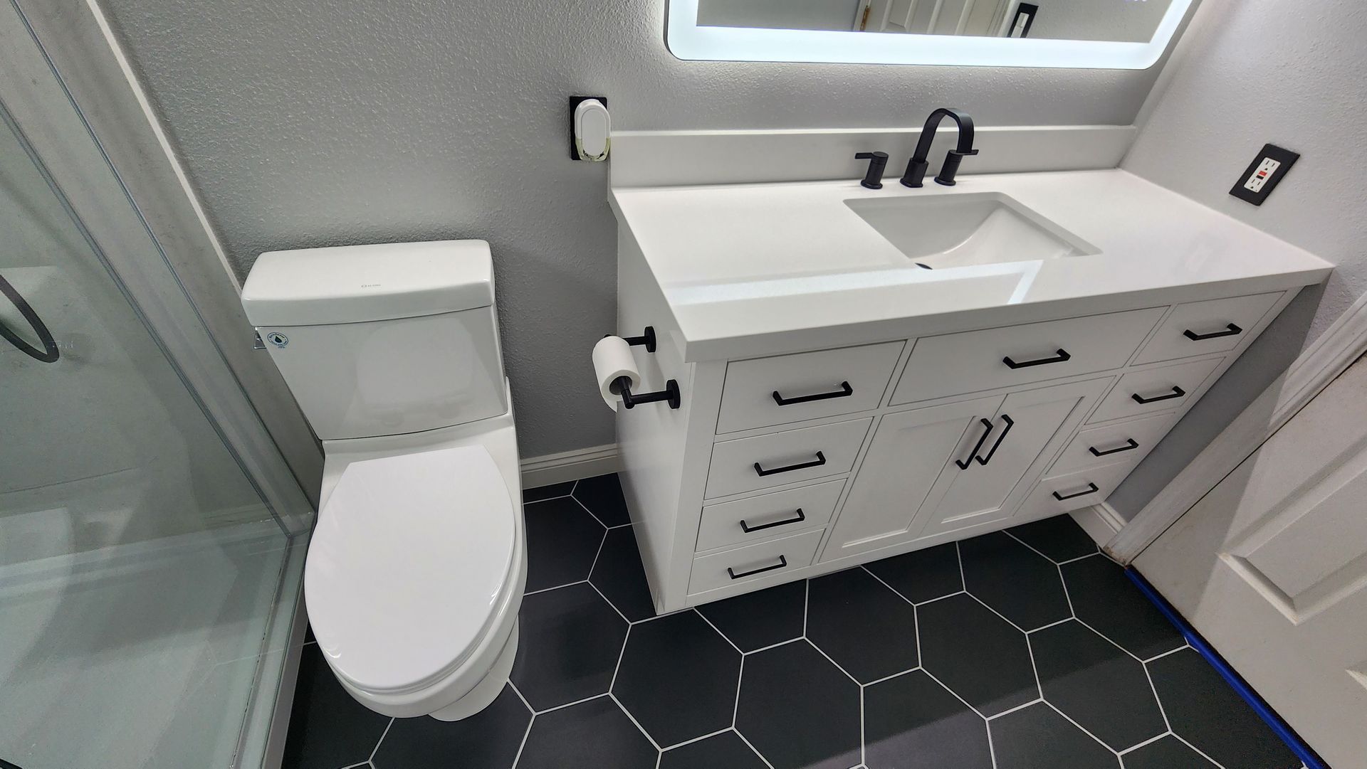 A bathroom with a toilet , sink , mirror and shower.