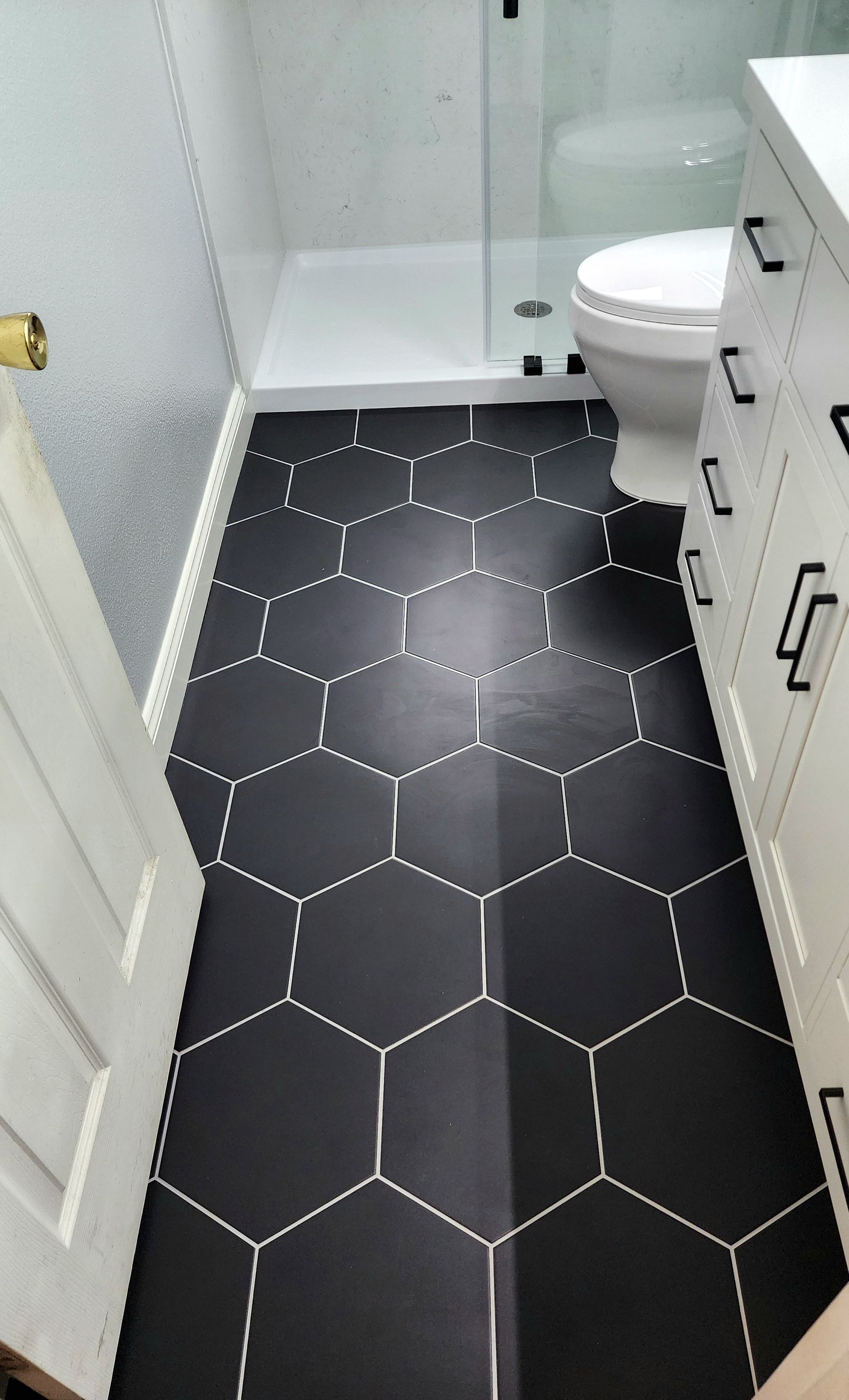 A bathroom with black tiles and a toilet