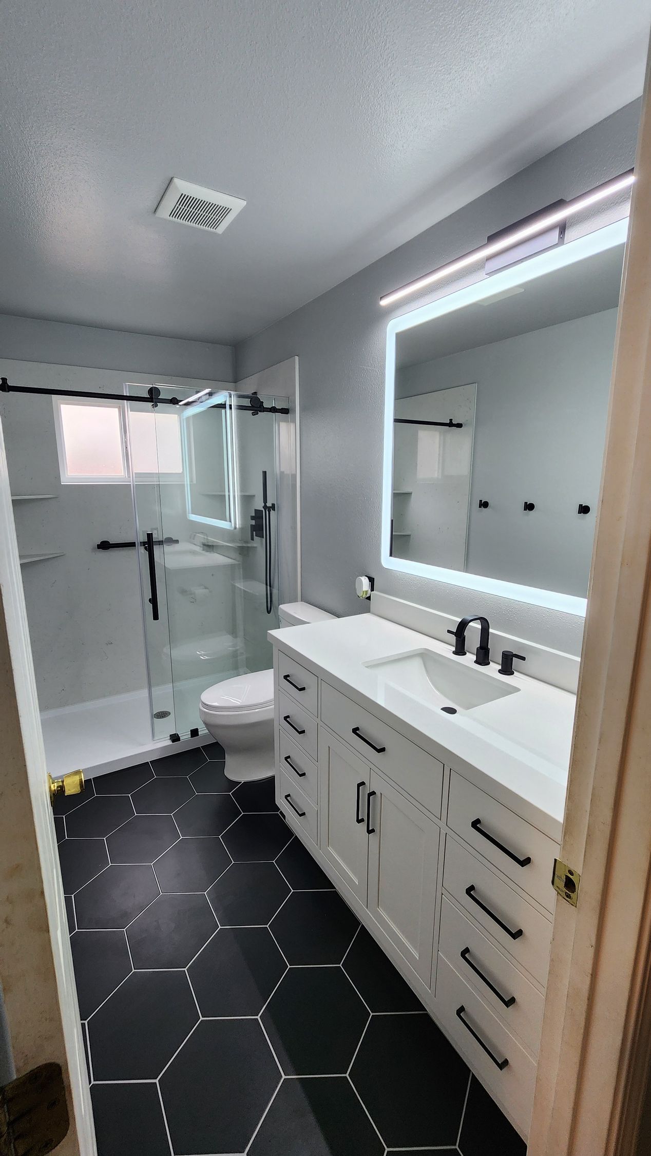 A bathroom with a sink , toilet , shower and mirror.