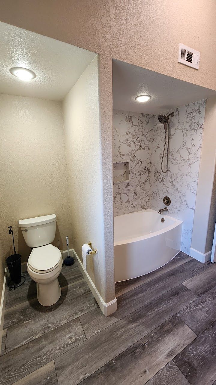 A bathroom with a toilet , bathtub and shower.