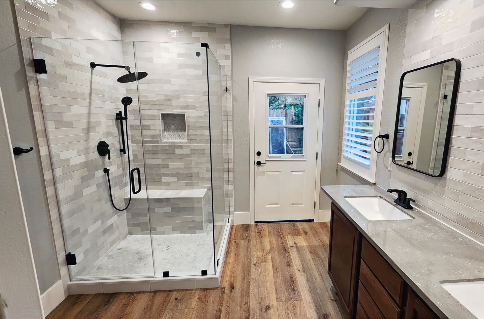 A bathroom with a walk in shower , sink and mirror.